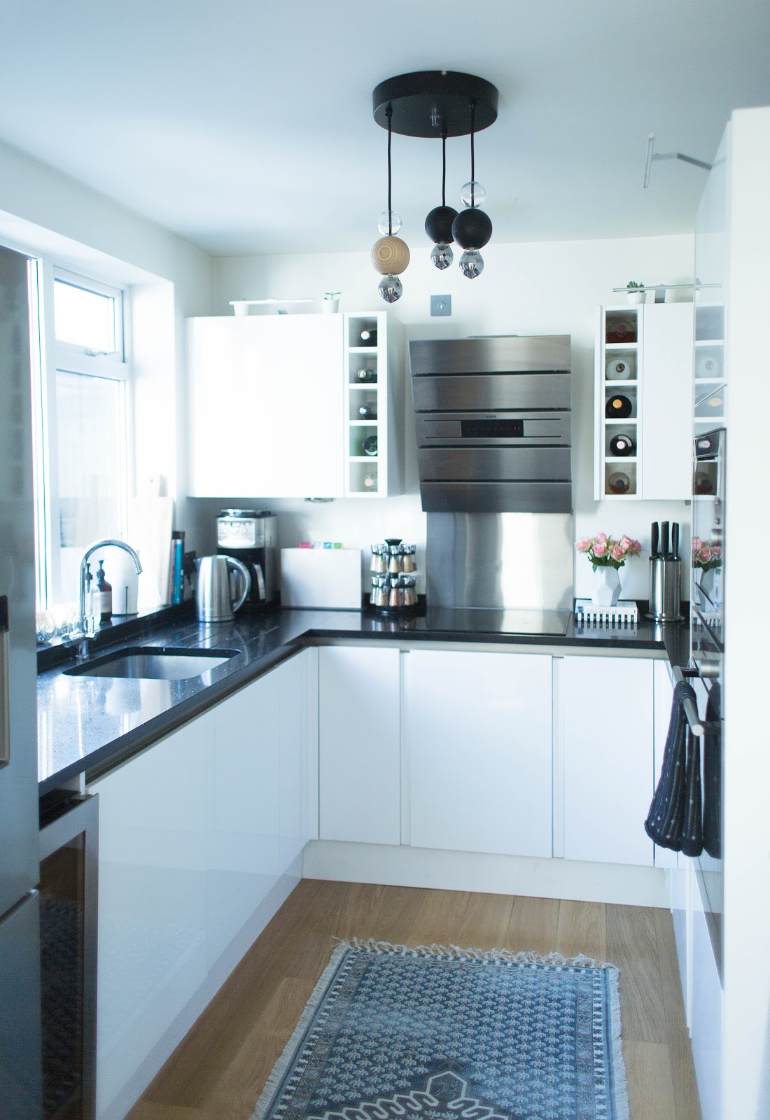 Magnet Integra kitchen with white handleless cabinets, quartz worktops and integrated appliances in a modern renovated home wtih a statement light and bohemian rug.
