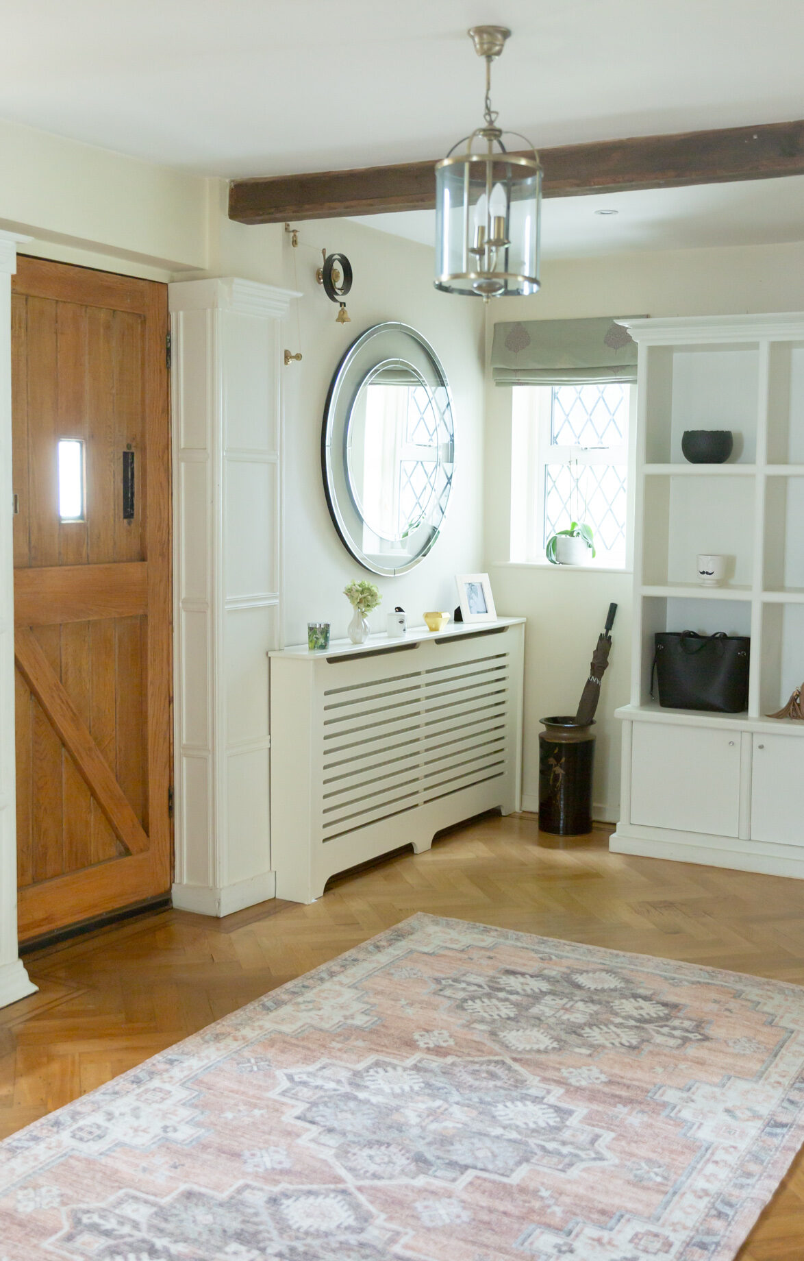 1920s house hallway with original wooden beams, large mirror, front door and vintage butler's bell used as a doorbell 