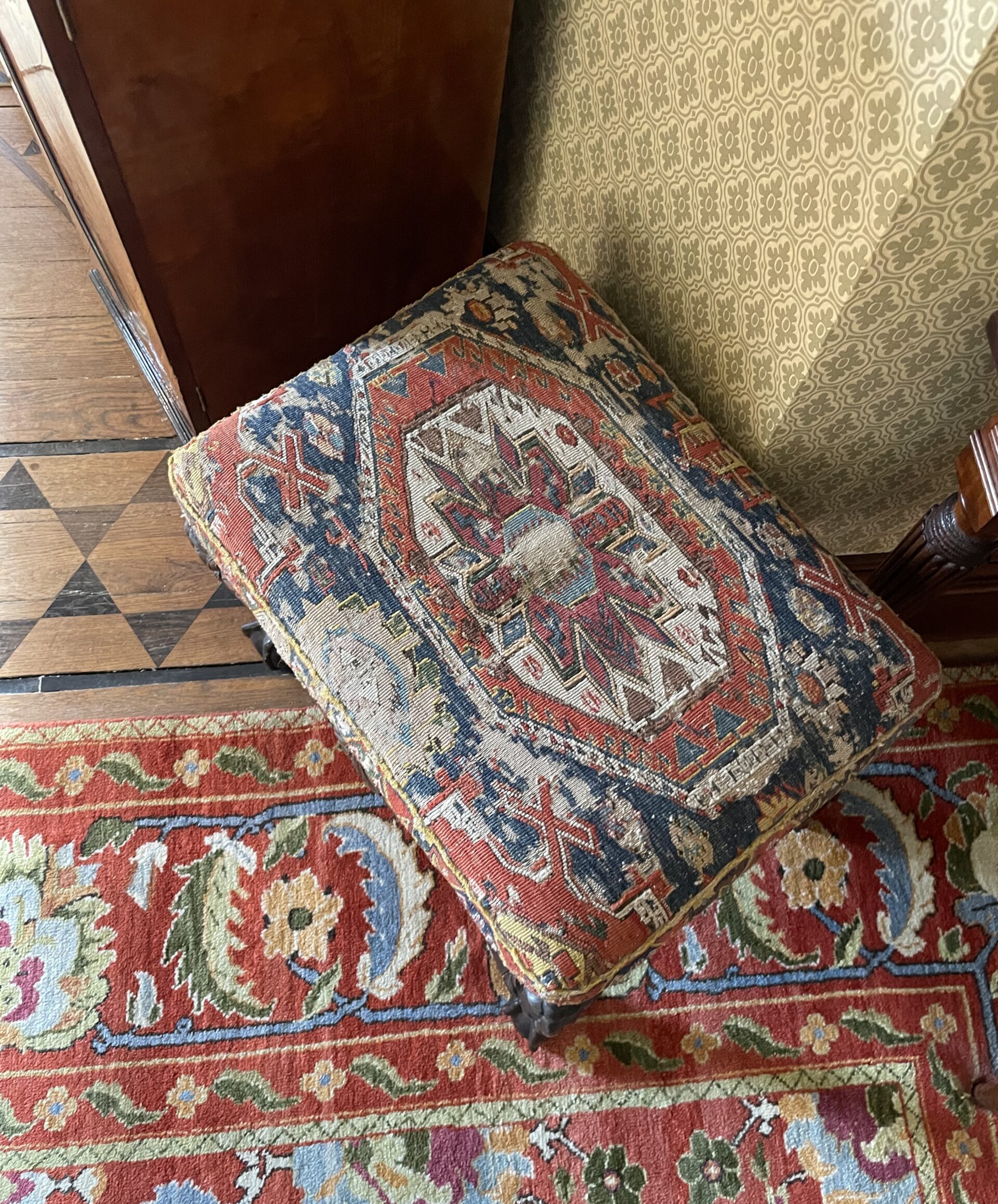 Pouffe upholstered in a colourful patterned vintage carpet 