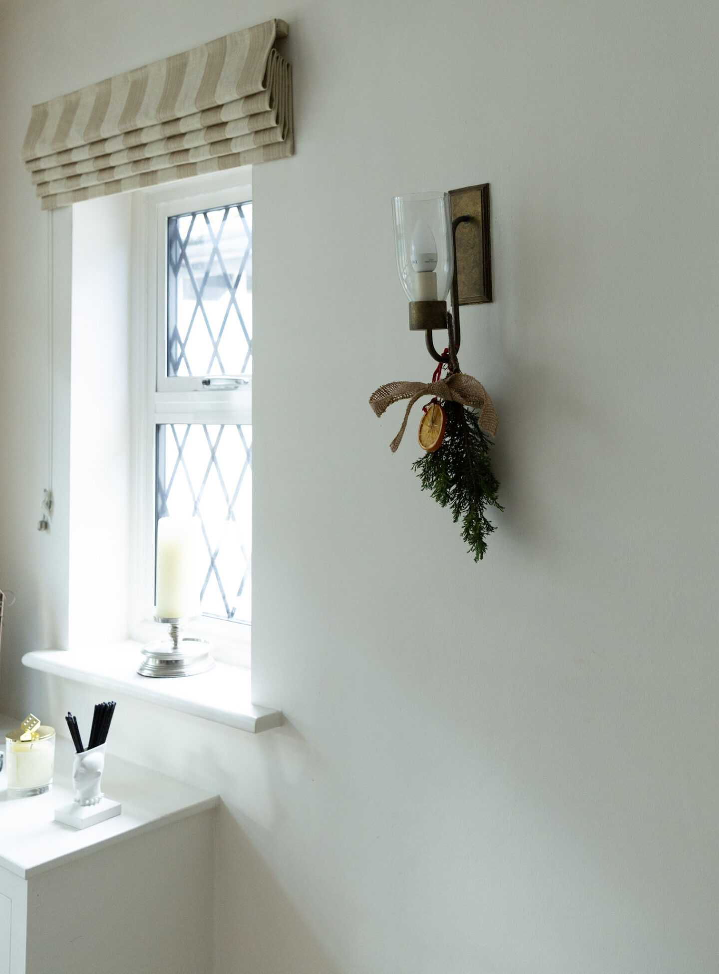 DIY Christmas Hanging Branch With Hessian Ribbon and Oranges Hanging on a Wall Light