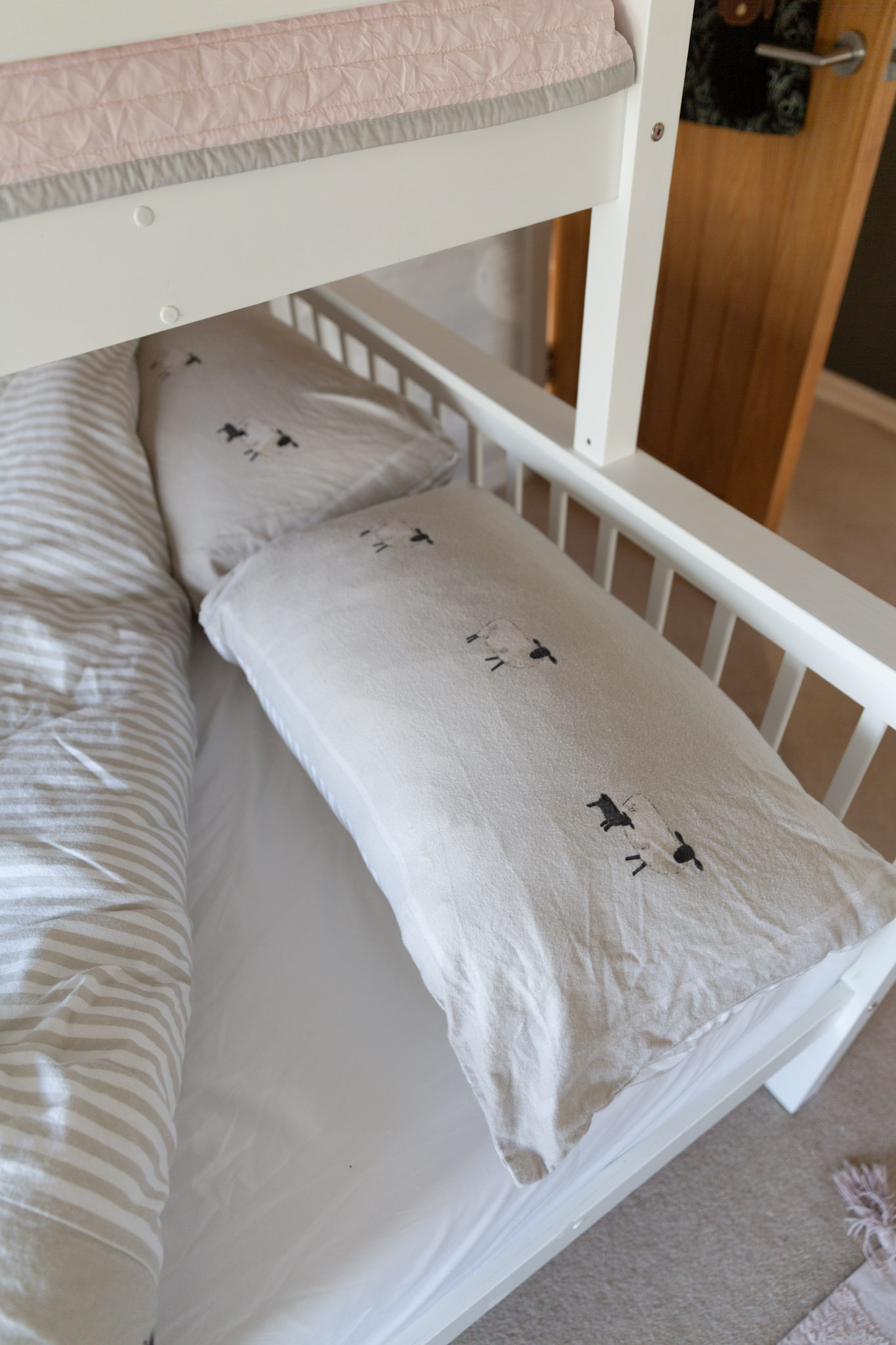 Beige sheep-patterned pillow covers and beige stripey bedding.