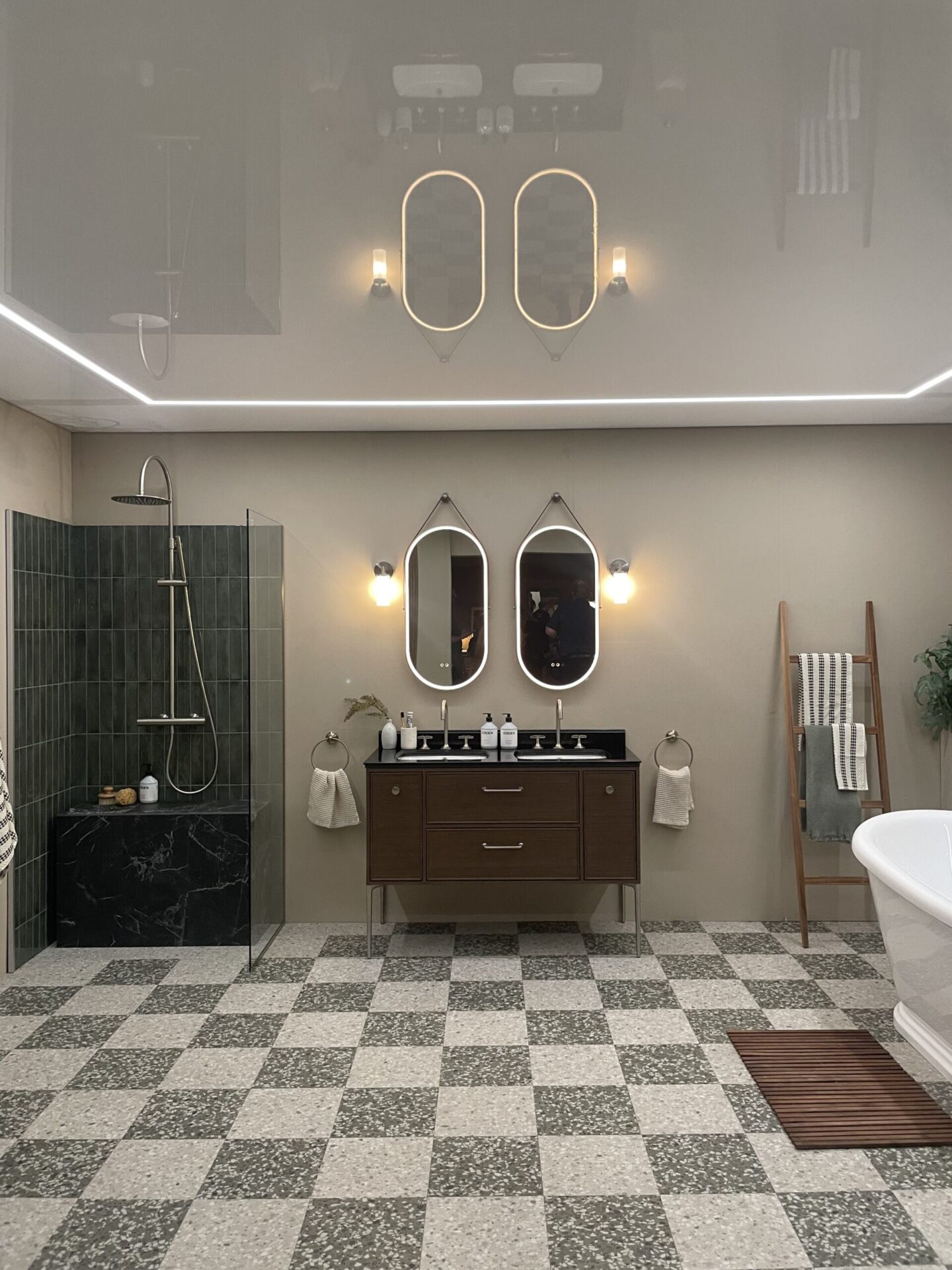 Modern bathroom with chequered floor, marble and brown accents with beige walls.