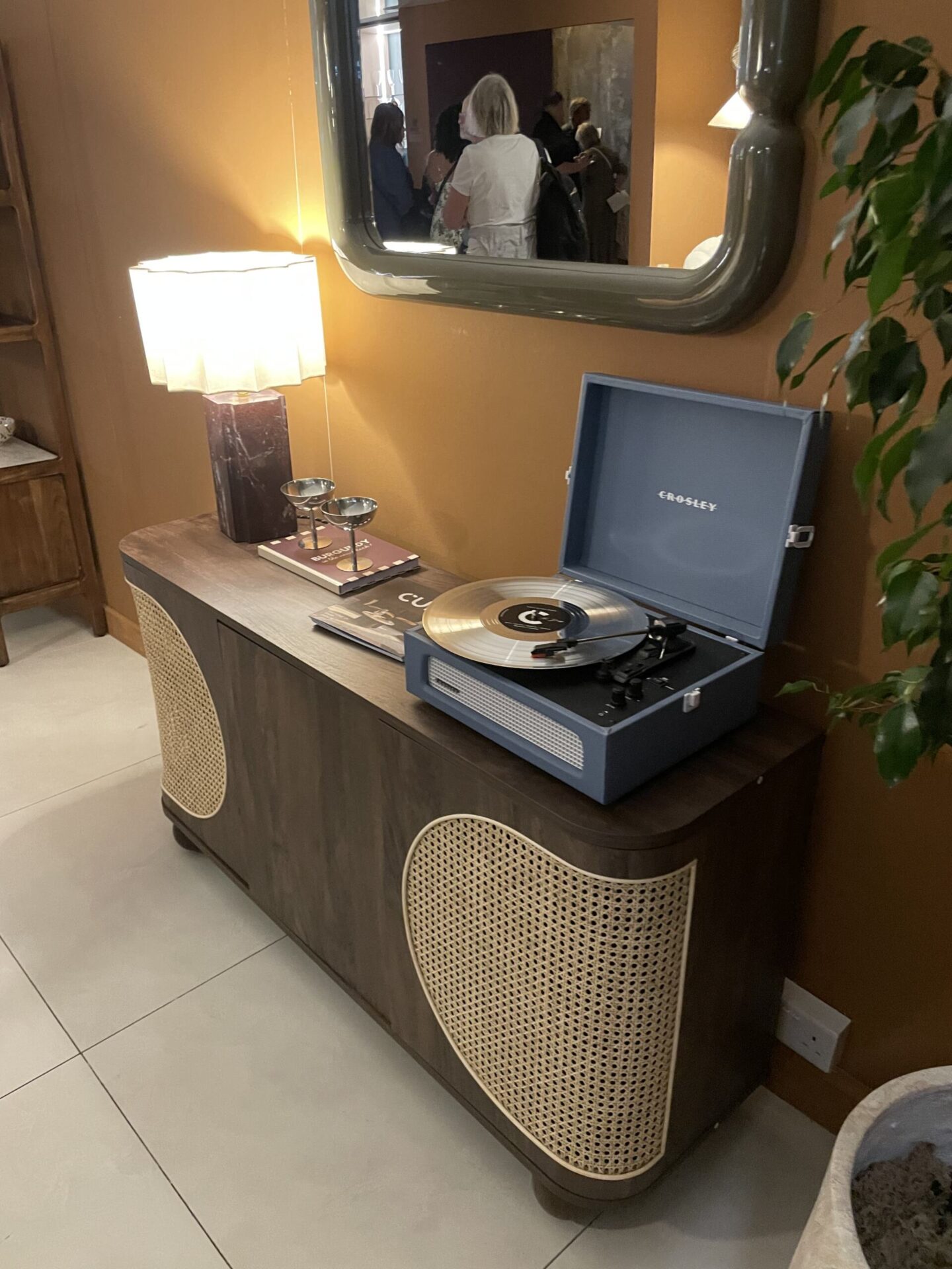 Curved dark wood side table with light rattan detailing.