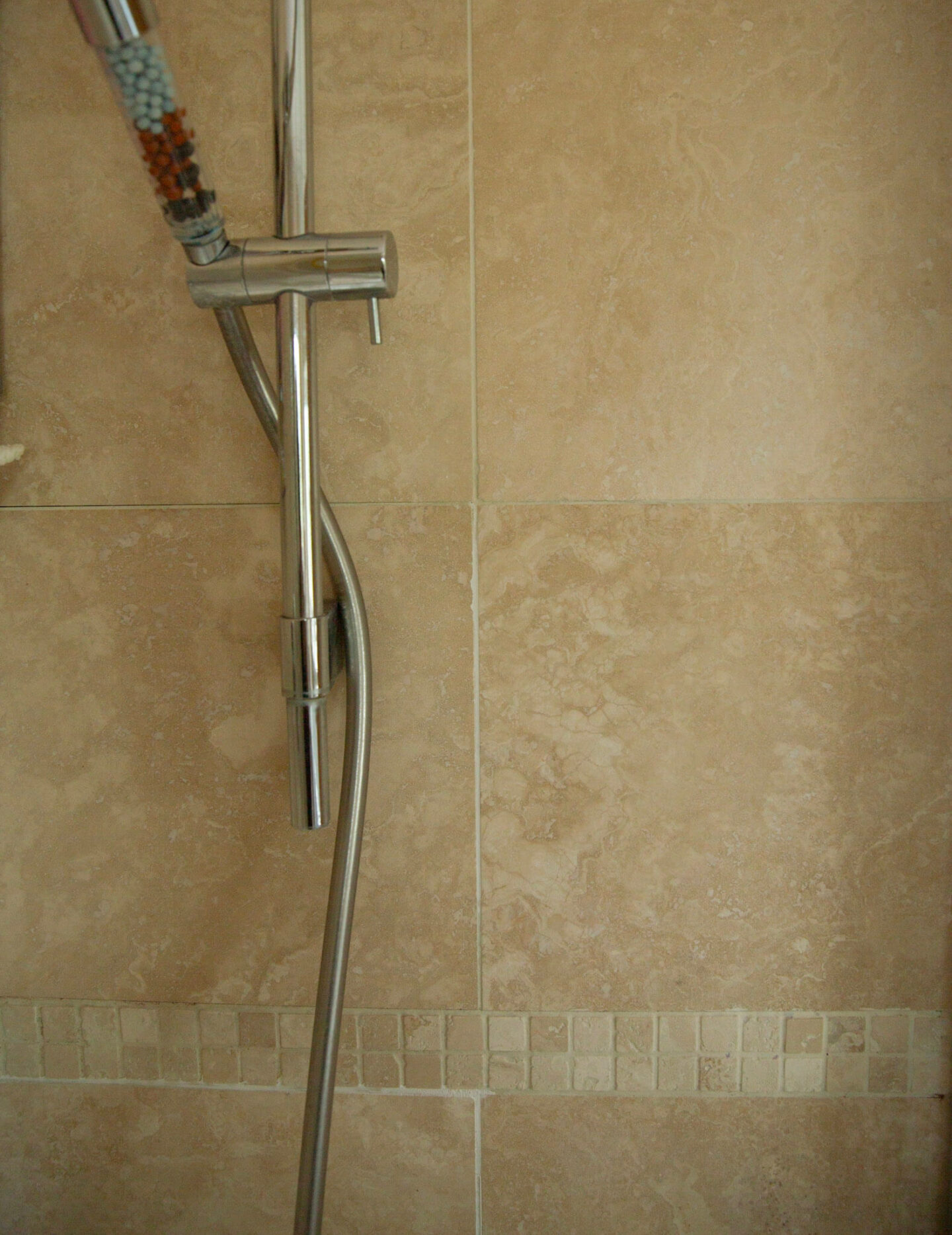 Newly repaired grout next to old grout on beige shower tiles