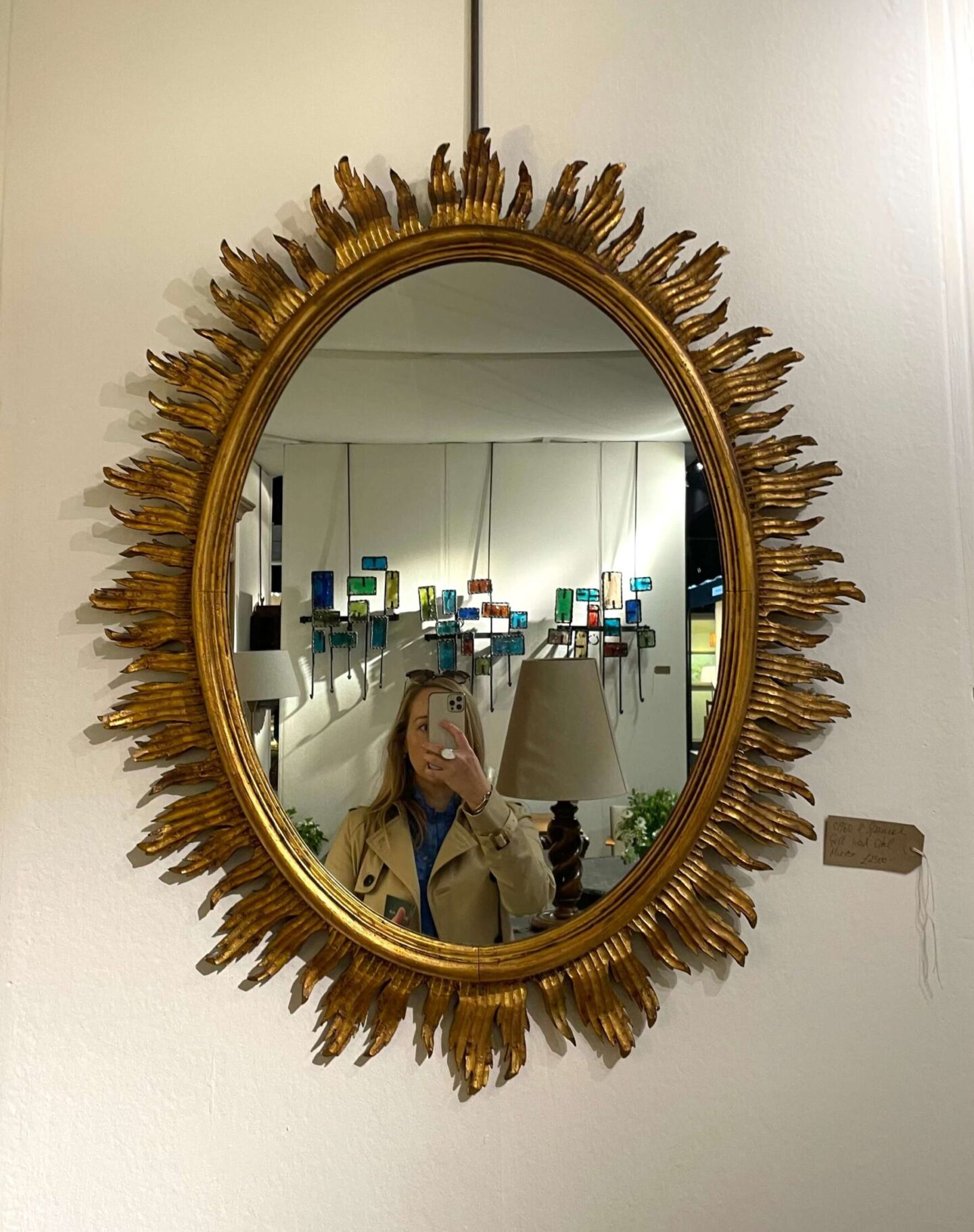 Antique sunburst mirror with carved wood and gilded oval sunburst frame on display at the Decorative Fair in London