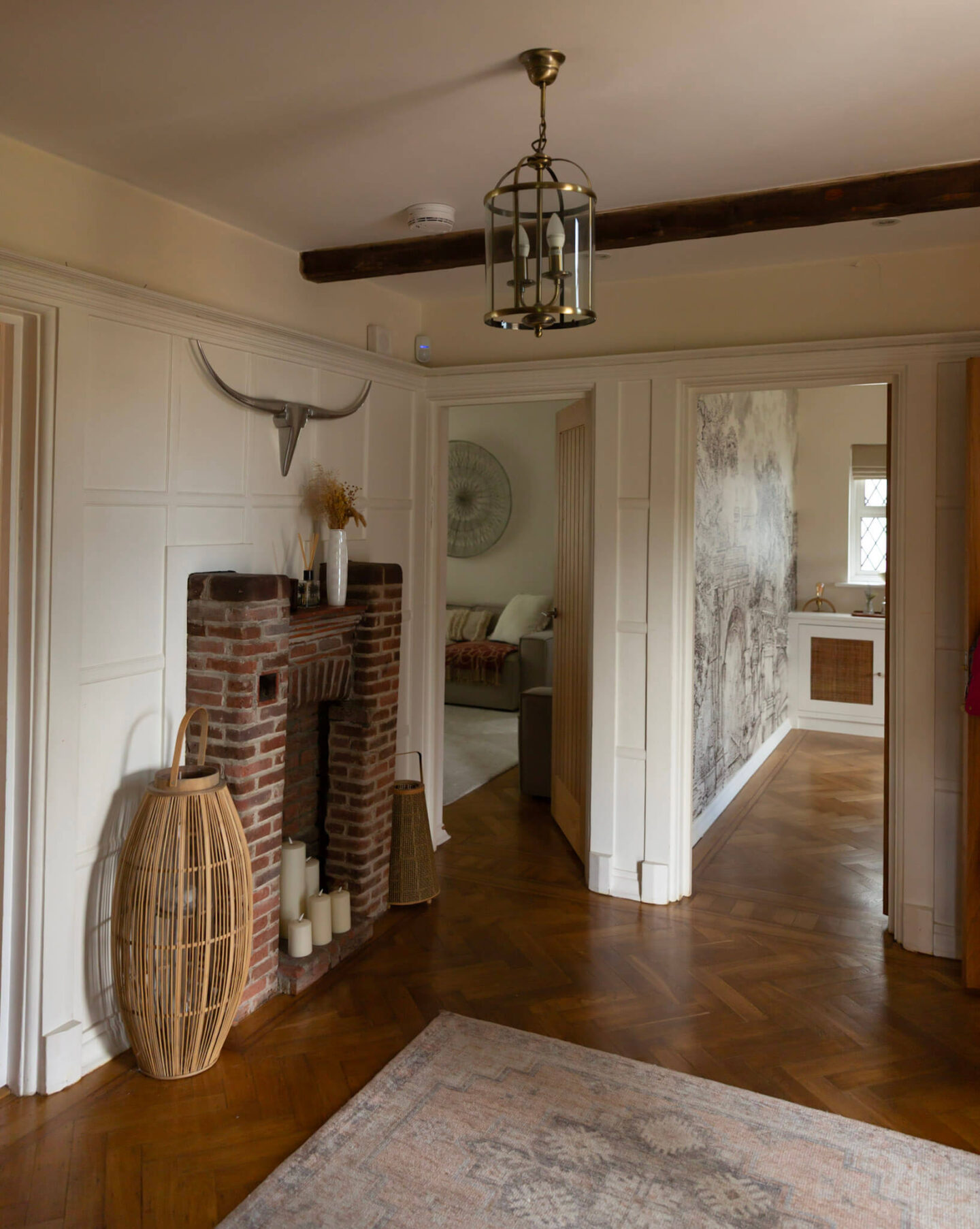 Newly decorated 1920s period house hallway with an original red brick fireplace, rustic wooden beams and original oak parquet flooring