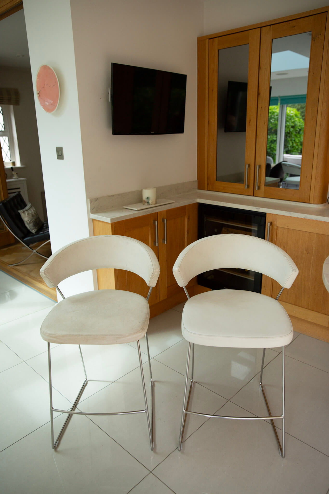 Side-by-side comparison of a worn greyed leather bar stool and the same stool after restoration to a bright white finish.
