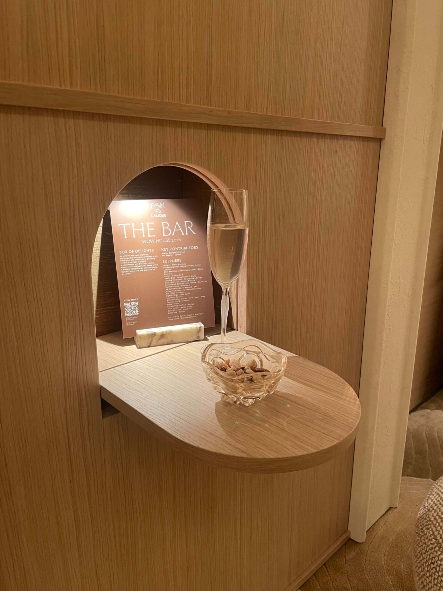 Elegant home bar design with light wood finishes, hidden drawers and integrated side tables