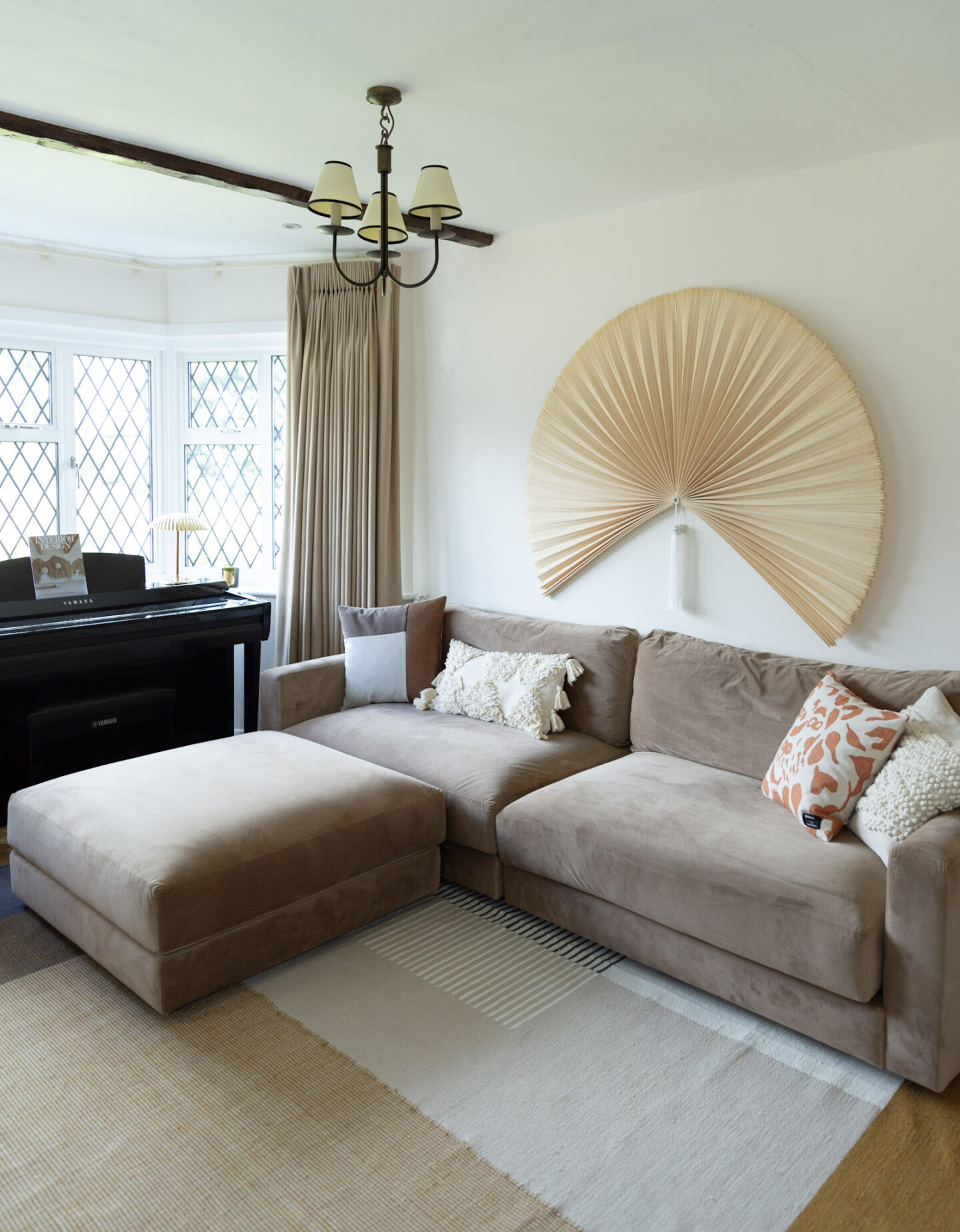 Beige velvet modular sofa and a footrest in a 1920s period property living room 