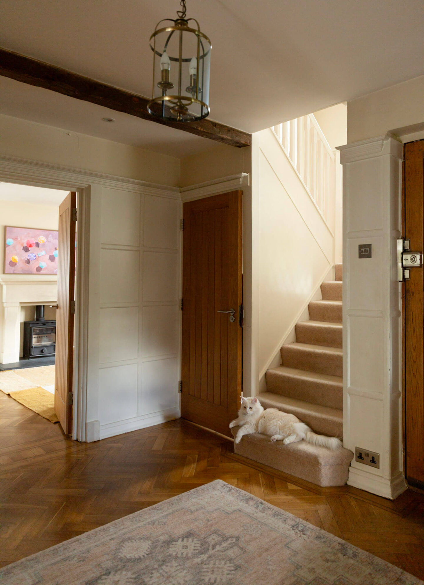 Original parquet flooring, wood panelling and wooden beams in a 1920s house hallway with cat on the stairs