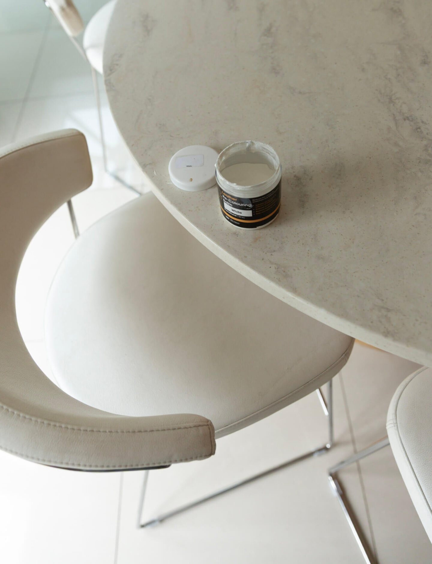 Application of recolouring balm to a white leather bar stool during restoration.