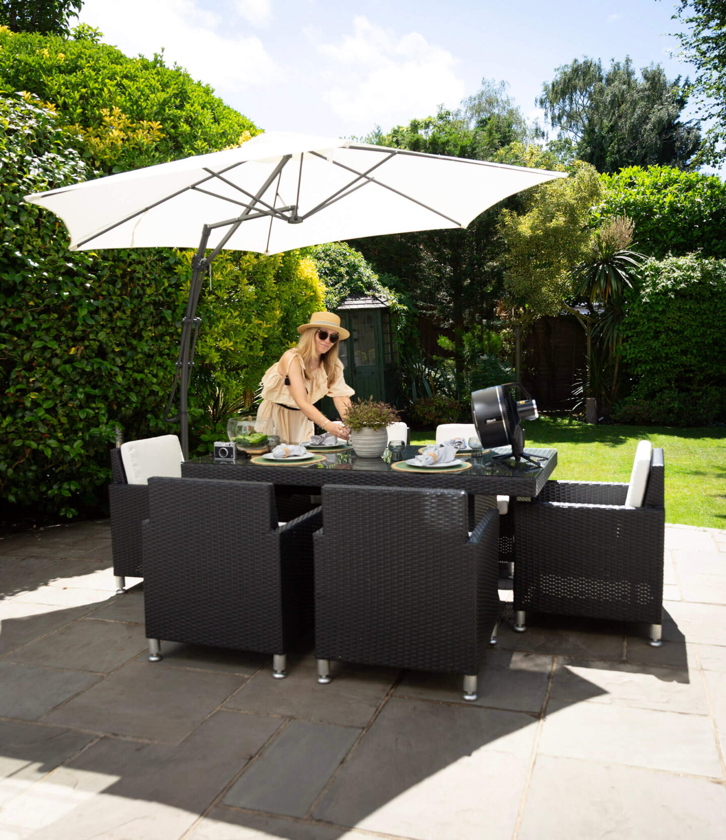 Arranging the garden dining table on our patio with the Shark FlexBreeze portable fan, surrounded by a leafy woodland garden