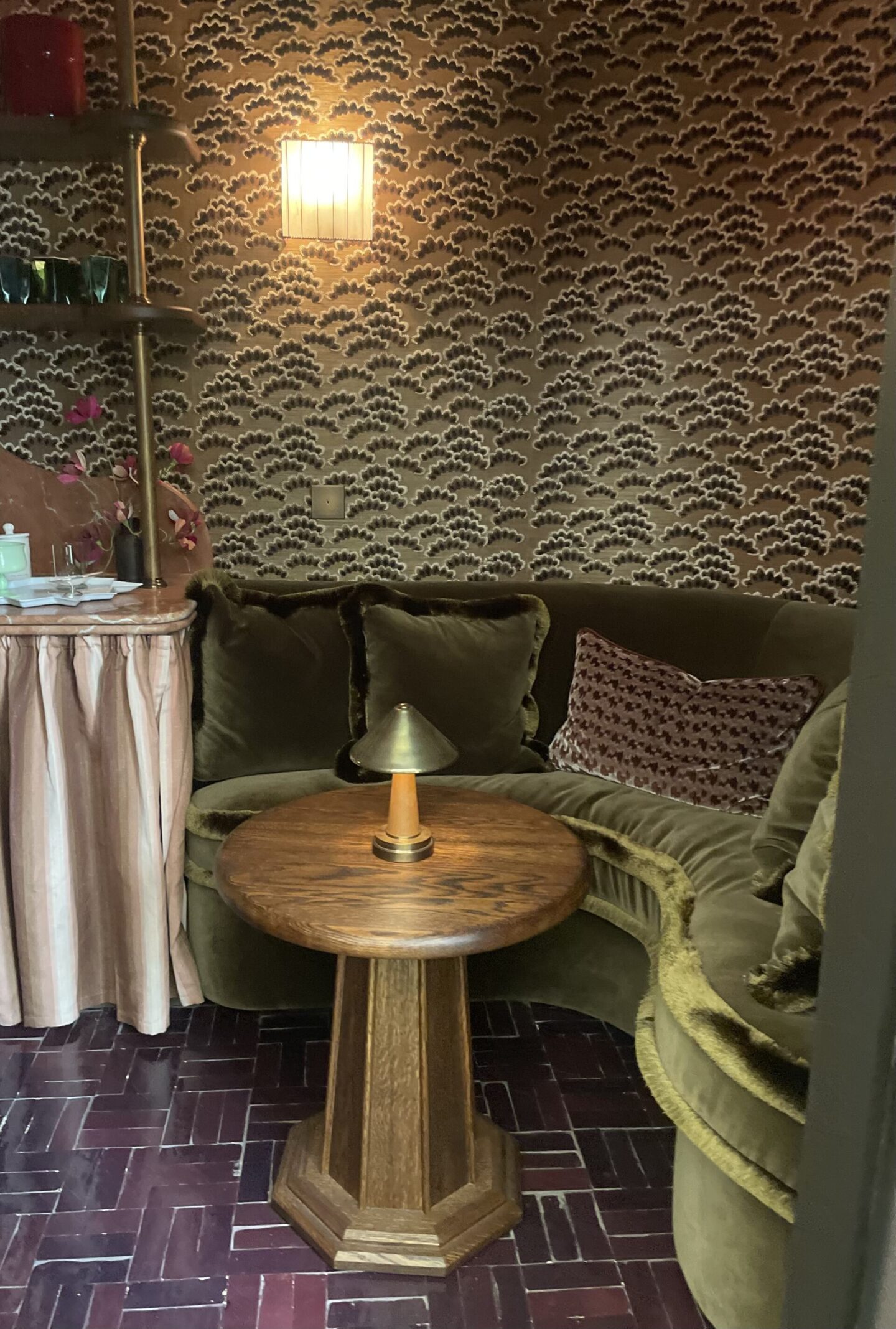 Moody interior with wallpapered walls, rich fabrics and layered textures creating a cosy atmosphere