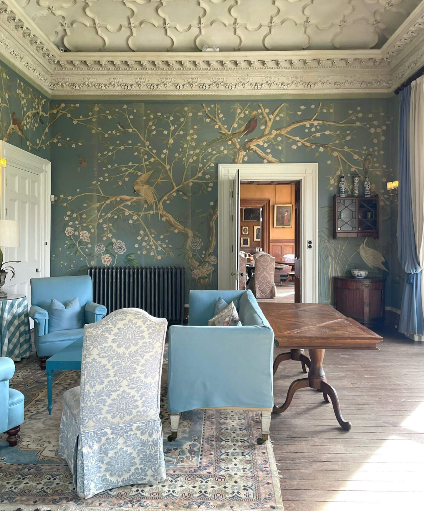 Formal room with woodland bird wallpaper, blue accents, and a decorative ceiling.