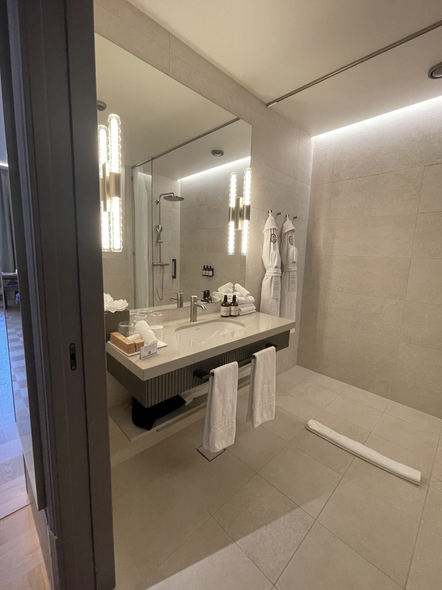 Large tiled bathroom with smart lighting and high-end fixtures.