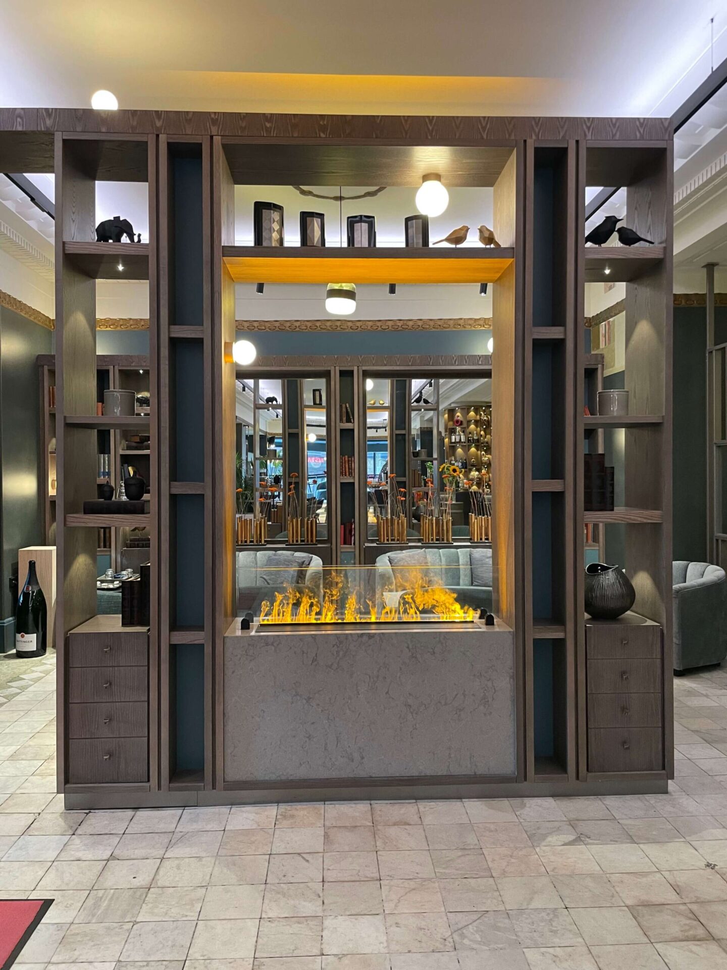 Decorative fireplace in the hotel lobby with seating and built-in shelves.