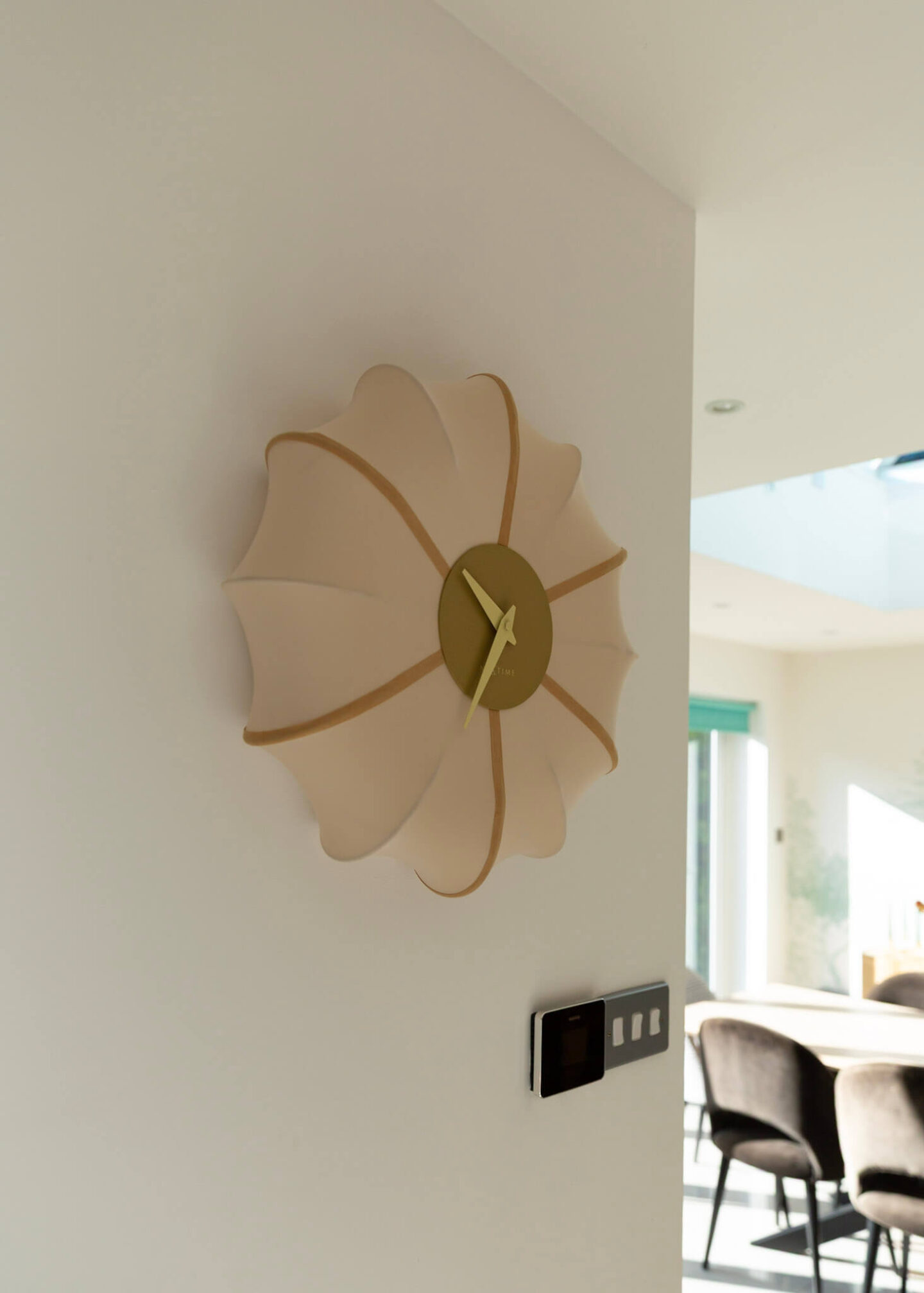 Close-up of the NeXtime Ultimo fabric wall clock showing its pleated fabric design and gold clock face