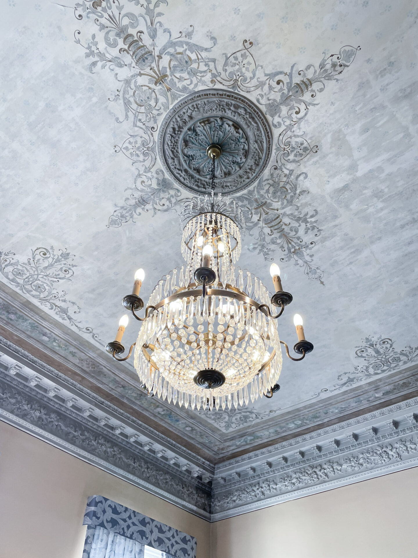 Ornate wallpapered ceiling with statement chandelier in the breakfast room at Hotel Haven Helsinki
